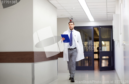 Image of doctor with clipboard walking along hospital