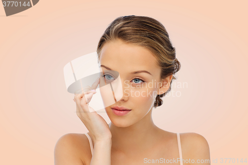 Image of young woman applying cream to her face