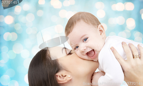 Image of happy mother kissing her baby over blue lights