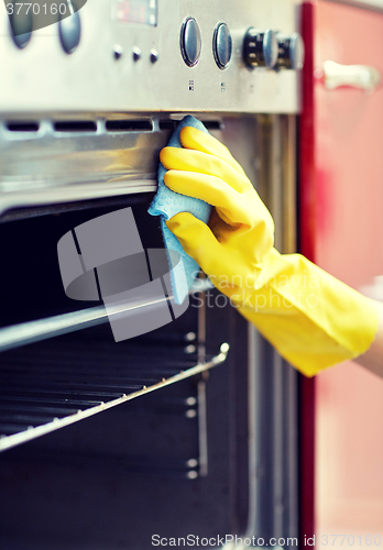 Image of close up of woman cleaning oven at home kitchen