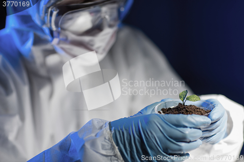 Image of close up of scientist with plant and soil in lab