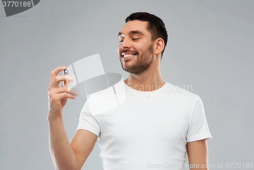 Image of smiling man with male perfume over gray background