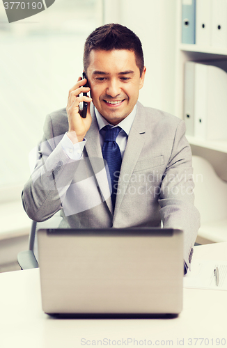 Image of smiling businessman with laptop and smartphone