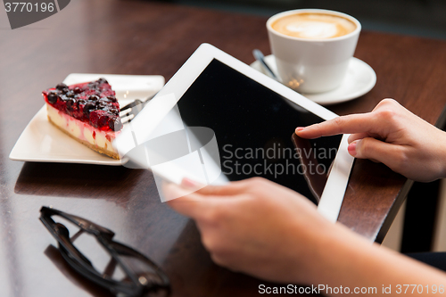 Image of close up of hands with tablet pc, coffee and cake