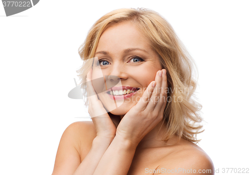 Image of smiling woman with bare shoulders touching face
