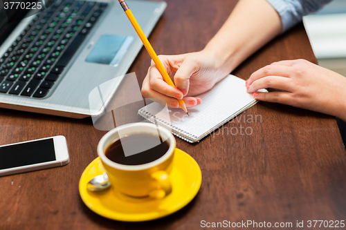 Image of close up of woman writing to notebook with pencil
