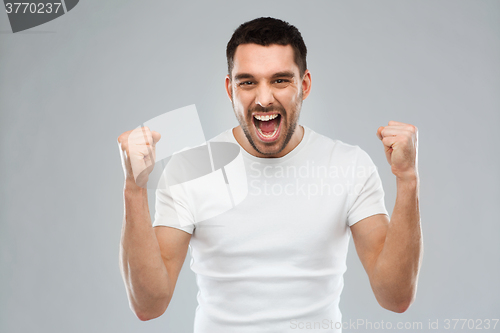 Image of young man celebrating victory over gray