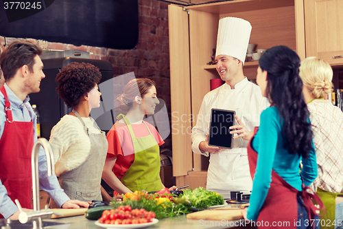 Image of happy friends with chef and tablet pc in kitchen