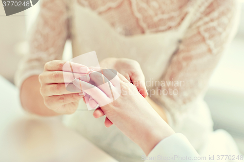 Image of close up of lesbian couple hands with wedding ring