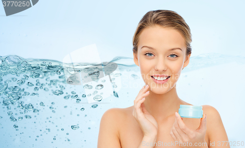 Image of happy young woman applying cream to her face