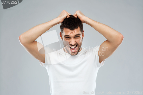 Image of crazy shouting man in t-shirt over gray background