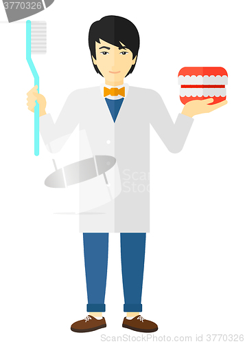 Image of Dentist with dental jaw model and toothbrush.