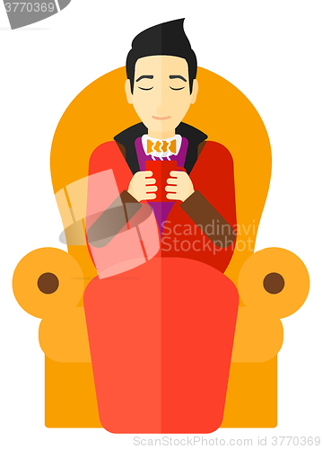 Image of Man sitting in chair with cup of tea.