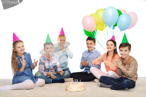 Image of happy children in party hats with birthday cake