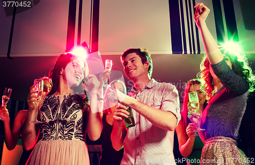 Image of smiling friends with wine glasses and beer in club