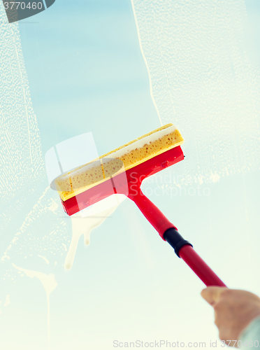 Image of close up of hand cleaning window with sponge