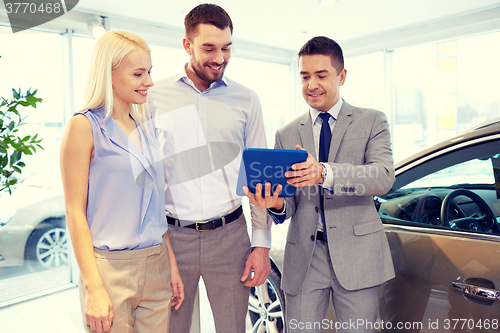 Image of happy couple with car dealer in auto show or salon
