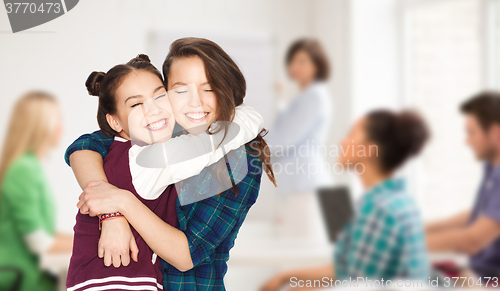 Image of happy teenage student girls hugging at school