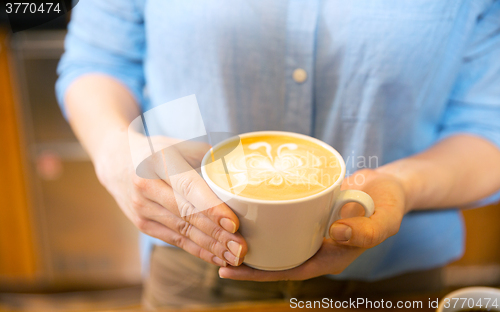 Image of close up of hands with latte art in coffee cup