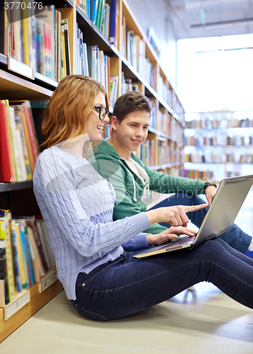 Image of happy students with laptop in library