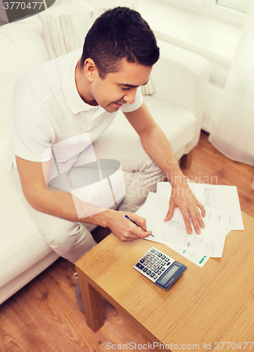 Image of man with papers and calculator at home