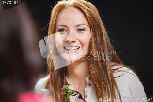 Image of happy young woman having dinner at restaurant