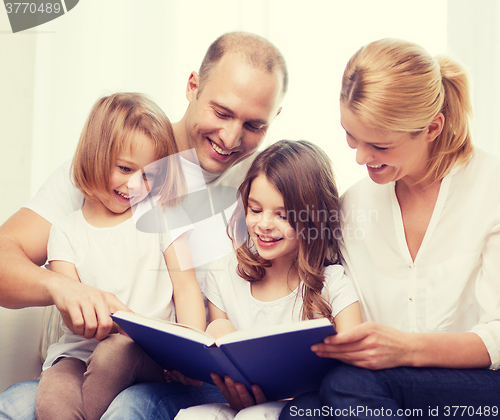 Image of smiling family and two little girls with book