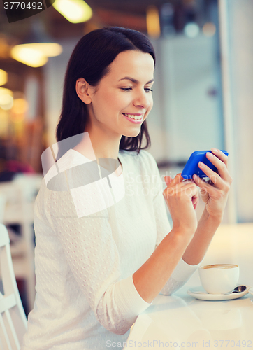 Image of smiling woman with smartphone and coffee at cafe