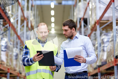 Image of worker and businessmen with clipboard at warehouse