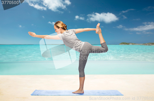 Image of woman making yoga in lord of the dance pose on mat