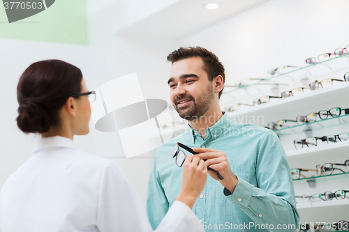 Image of optician showing glasses to man at optics store