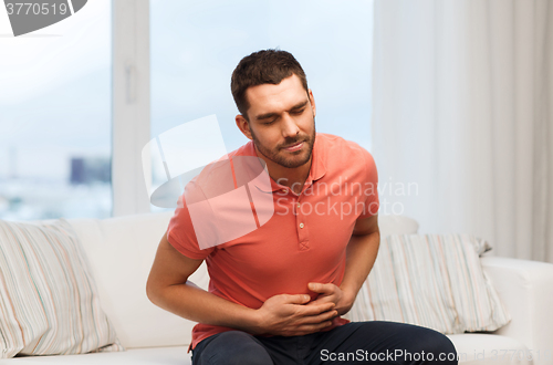 Image of unhappy man suffering from stomach ache at home