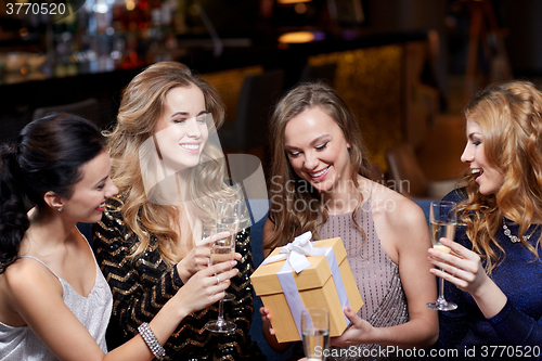 Image of happy women with champagne and gift at night club