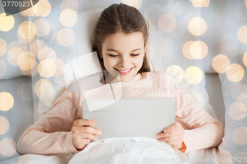 Image of happy girl lying in bed with tablet pc at home