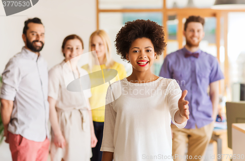 Image of woman making handshake over creative office team