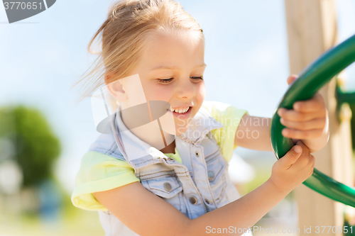 Image of happy little girl climbing on children playground