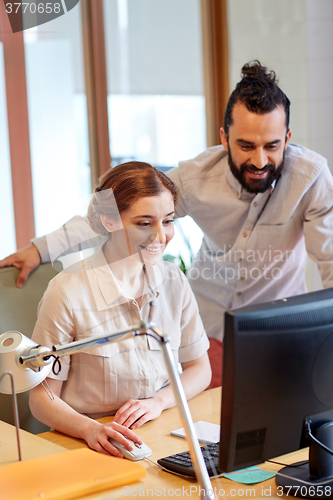 Image of happy creative team with computer in office