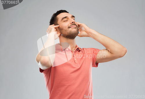 Image of happy man listening to music over gray background