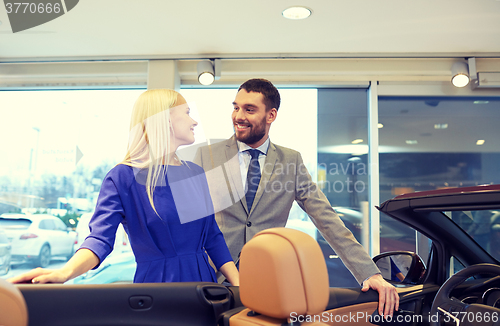 Image of happy couple buying car in auto show or salon