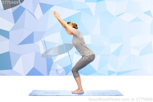 Image of woman making yoga in chair pose on mat