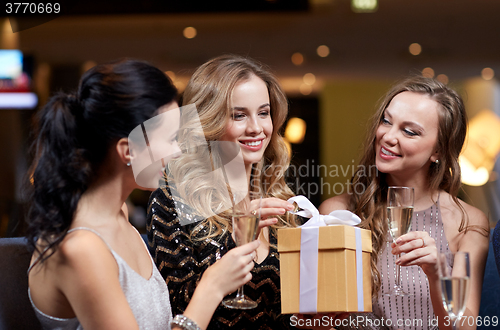 Image of happy women with champagne and gift at night club