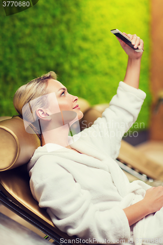 Image of beautiful young woman with smartphone at spa