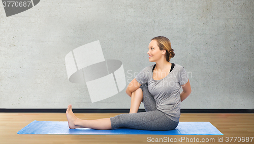 Image of woman making yoga in twist pose on mat