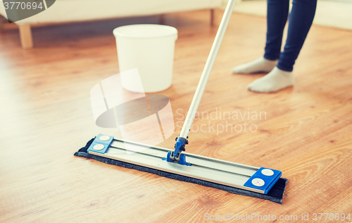 Image of close up of woman with mop cleaning floor at home