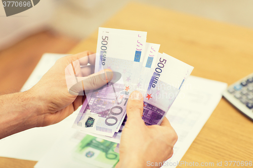 Image of close up of man hands counting money at home