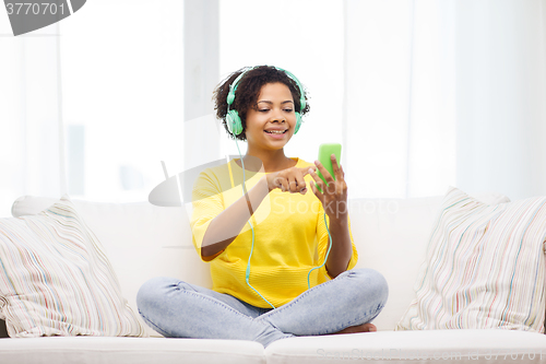 Image of happy african woman with smartphone and headphones