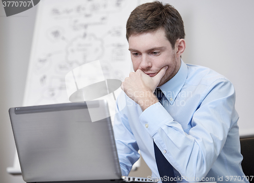 Image of businessman sitting with laptop in office