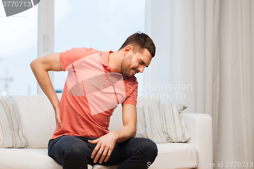 Image of unhappy man suffering from backache at home