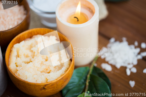 Image of close up of natural body scrub and candle on wood