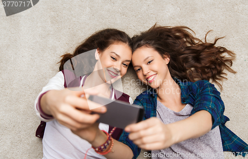 Image of happy teenage girls on floor and taking selfie